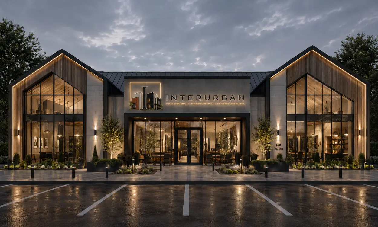 Interurban, West Plano: a two-story office building in limestone with a cedar-clad gable and full-height glazing, at dusk